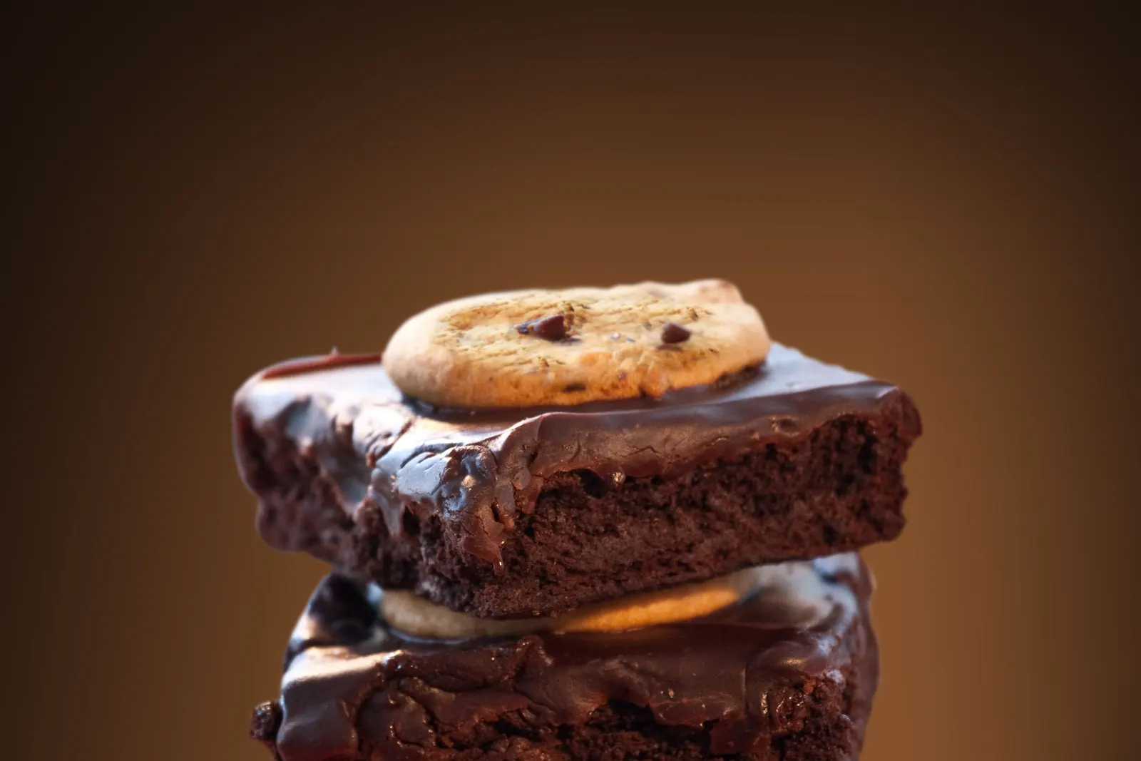 A stack of chocolate brownies topped with a cookie