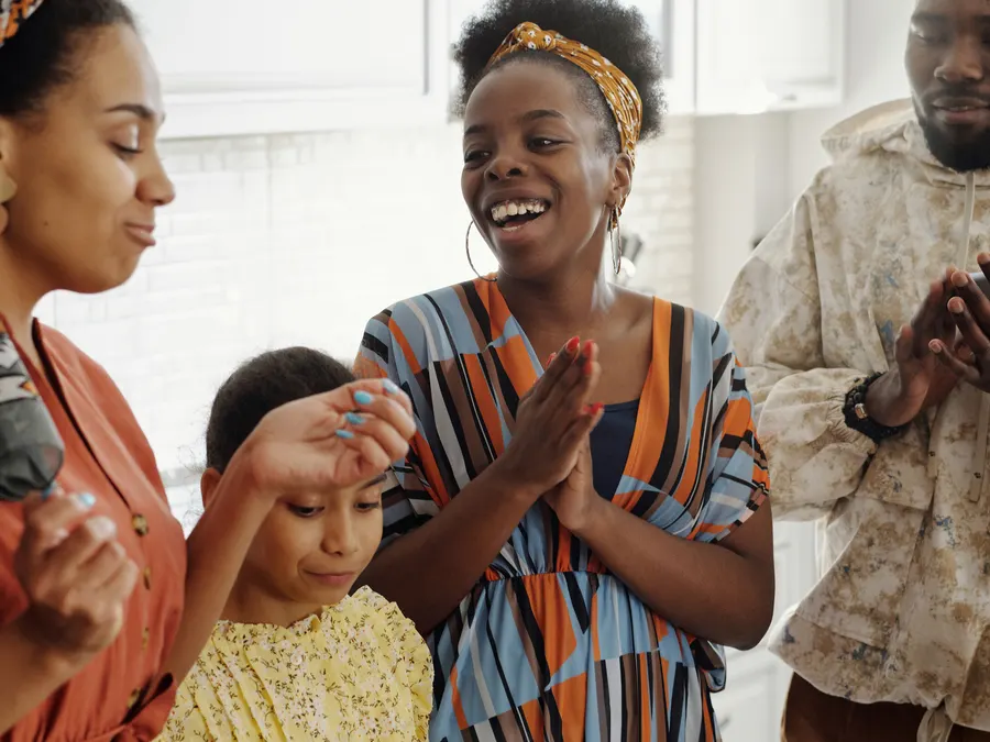 A family smiling and clapping together around the kitchen counter after sharing a homemade cake