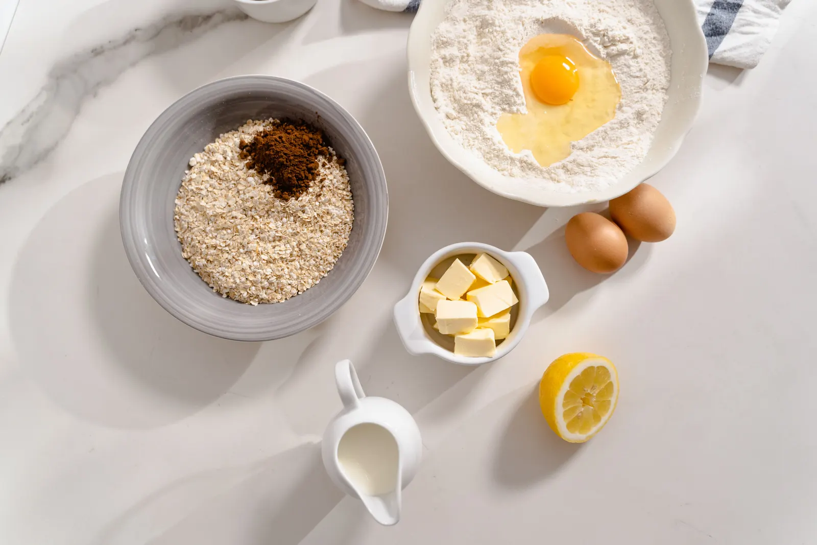 An overhead view of baking ingredients including flour and eggs in a ceramic bowl