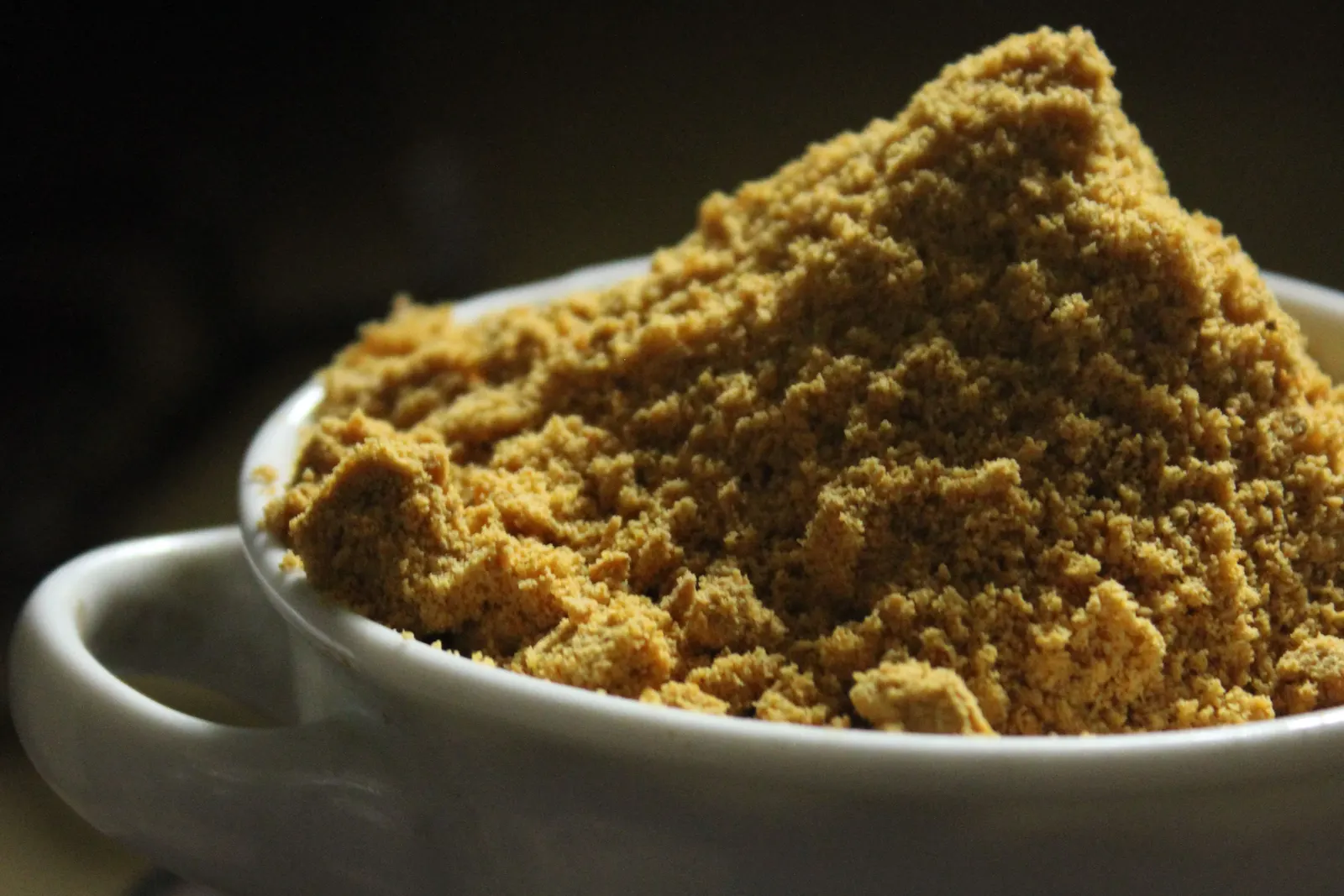 A close-up of brown sugar in a white ceramic bowl