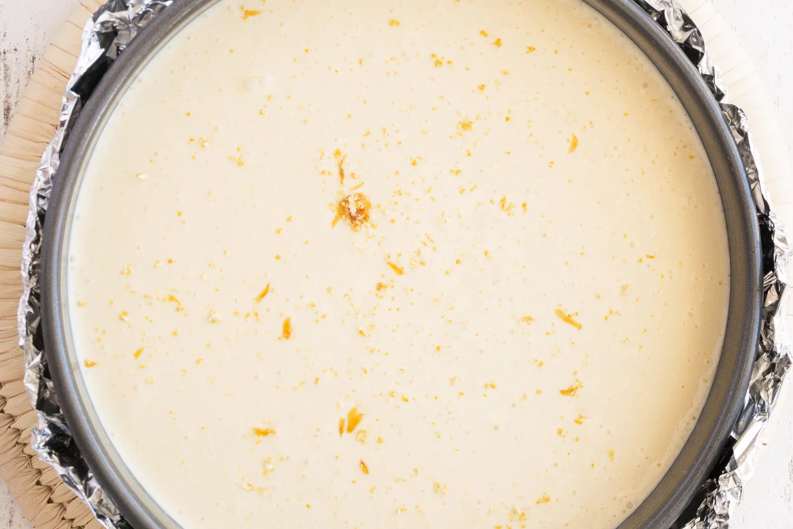 An overhead view of cheesecake batter in a round baking pan, ready to bake