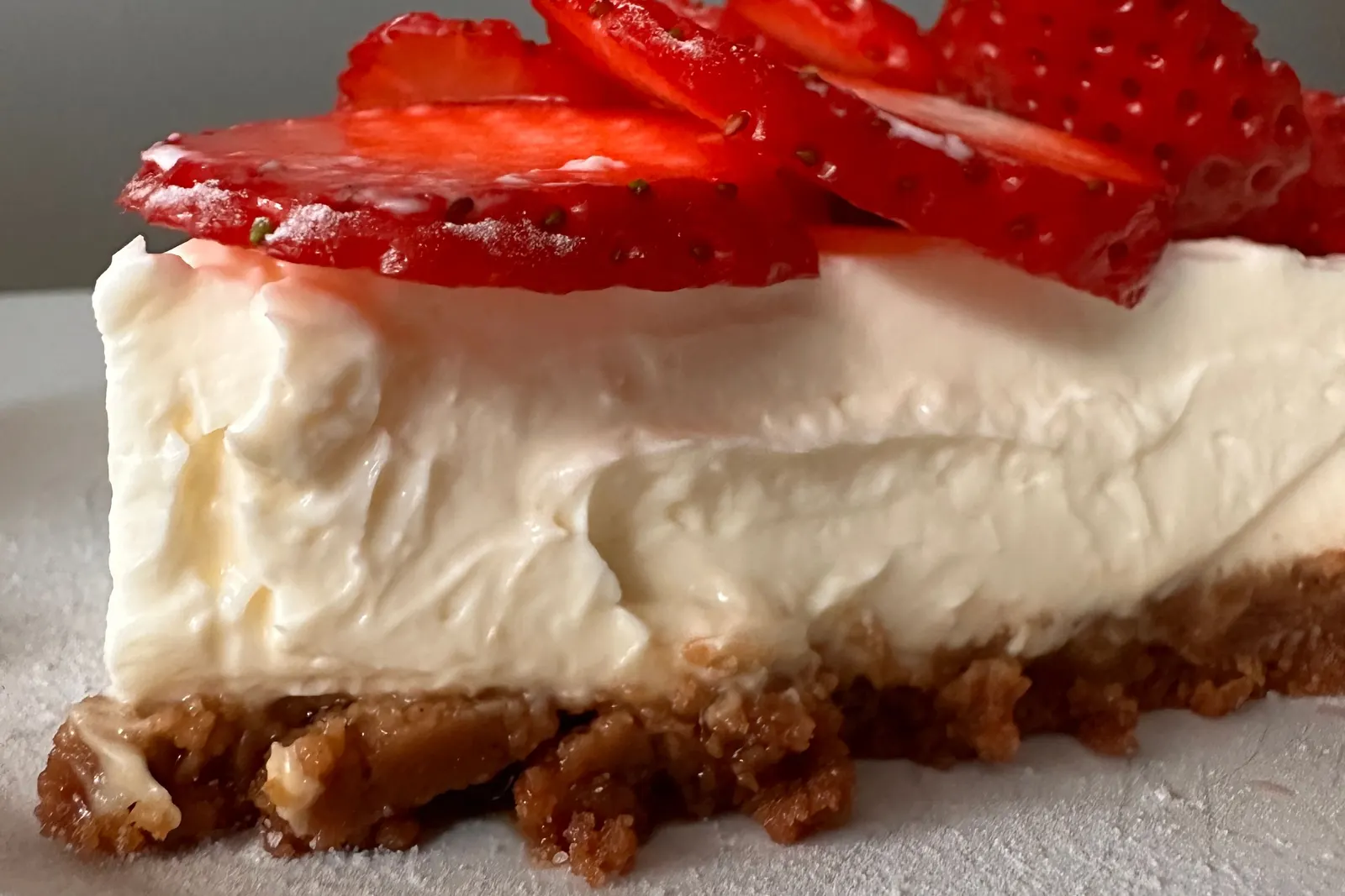 A slice of cheesecake topped with fresh strawberries