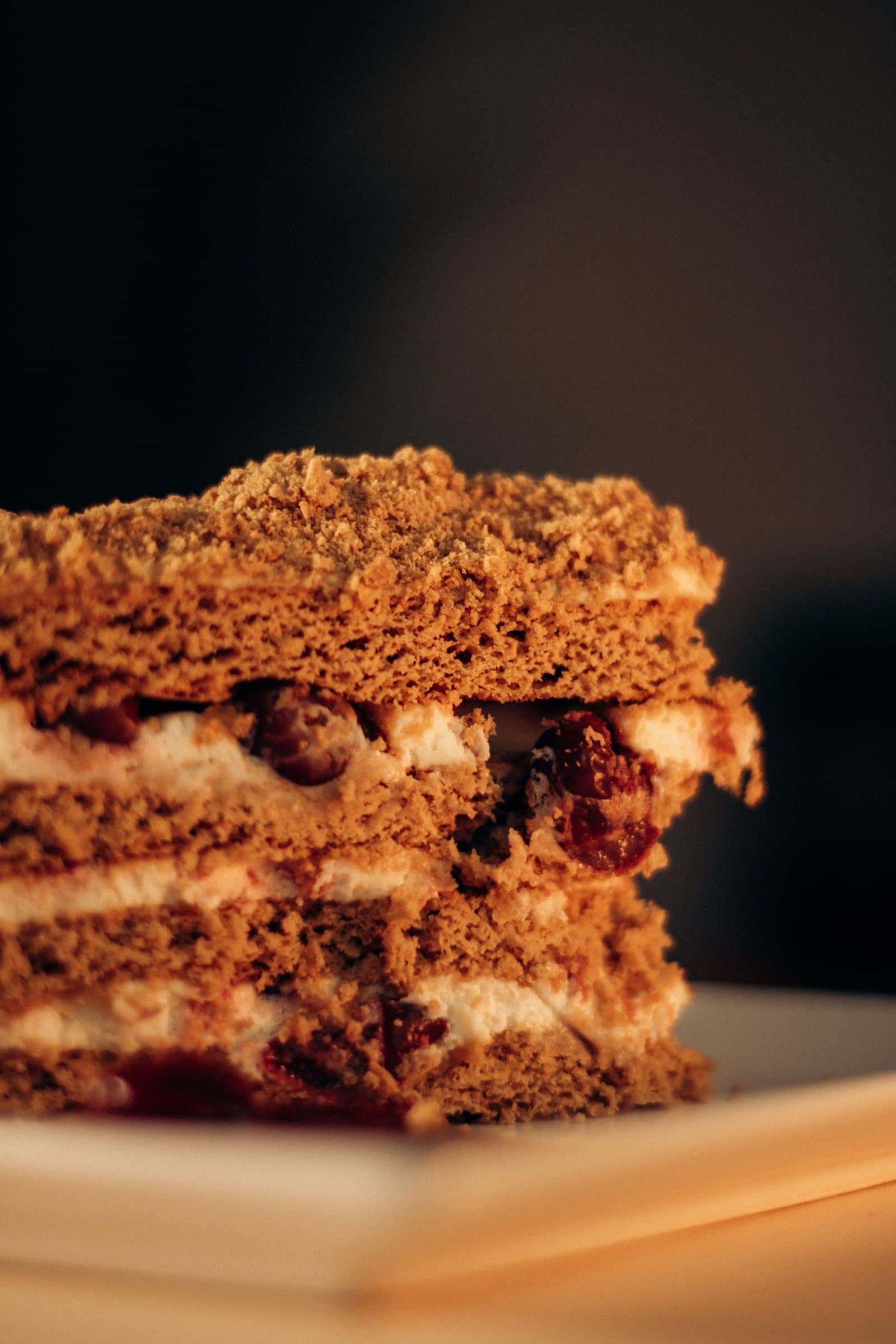 A close-up cross-section of a layered cake showing cake layers, cream filling, and fruit between each layer