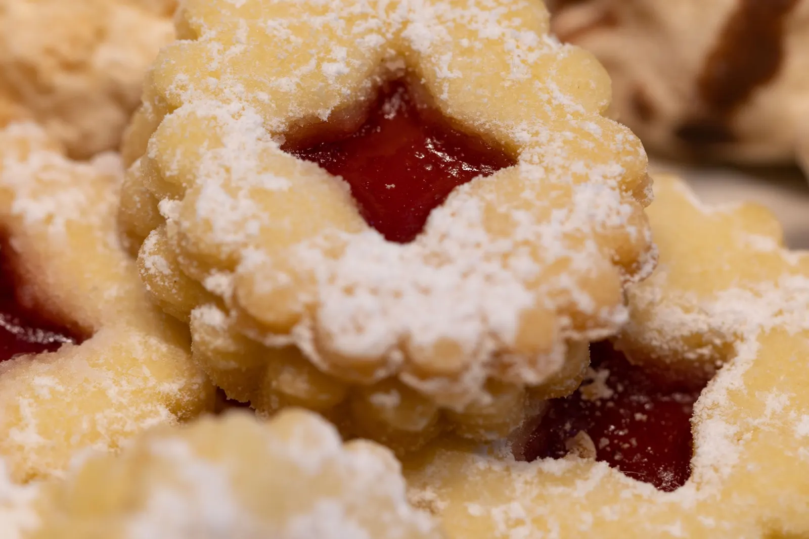 Linzer cookies with a cut-out window filled with raspberry jam, dusted with powdered sugar
