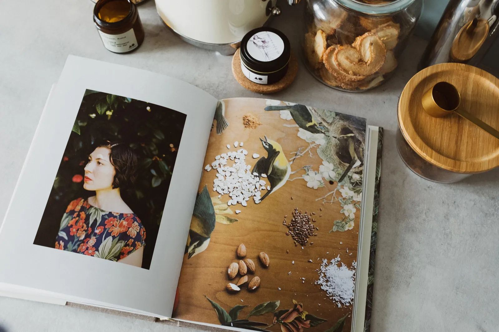 An open recipe book on a kitchen counter among spice jars