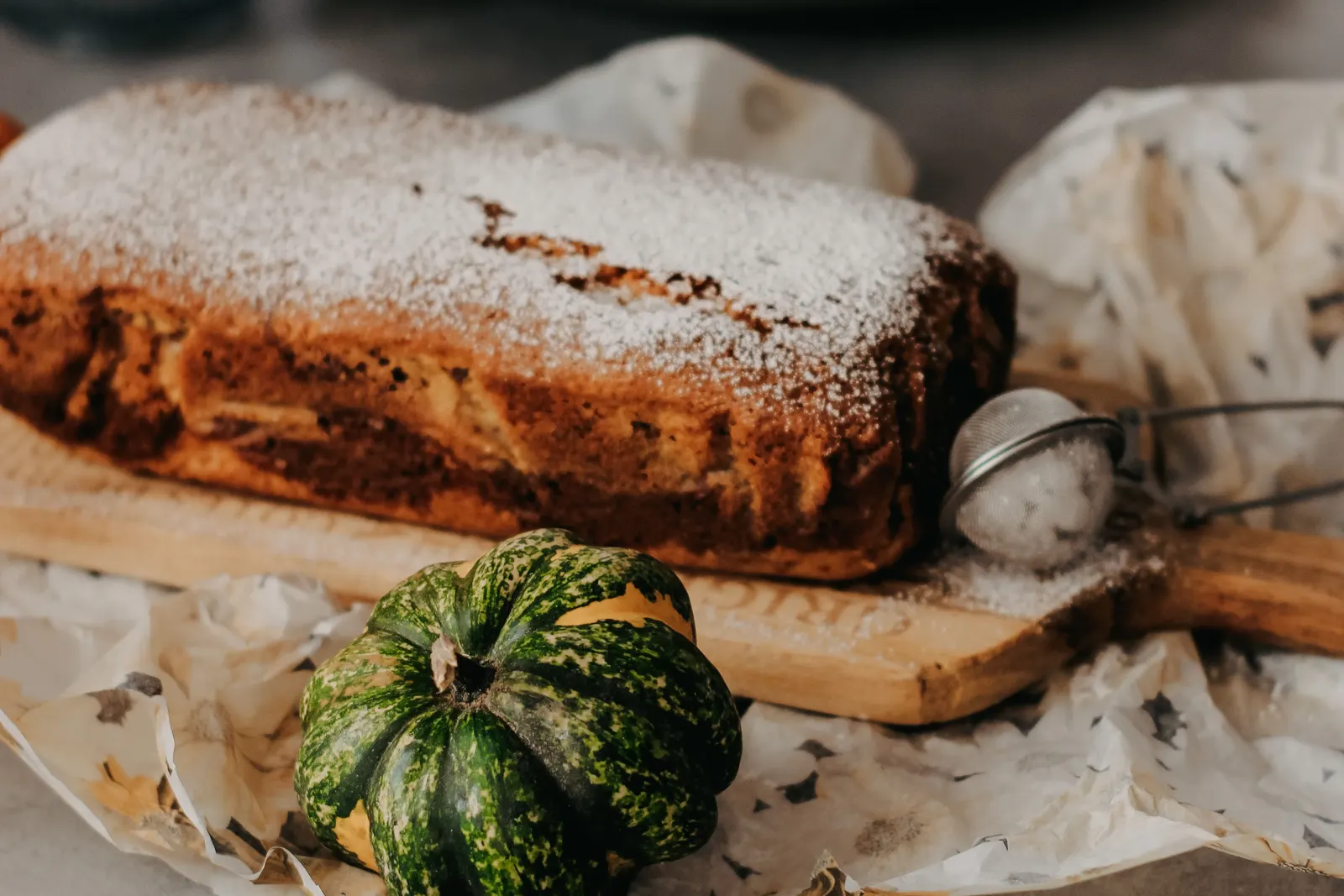 A whole homemade pumpkin bread loaf displayed with autumn decorations