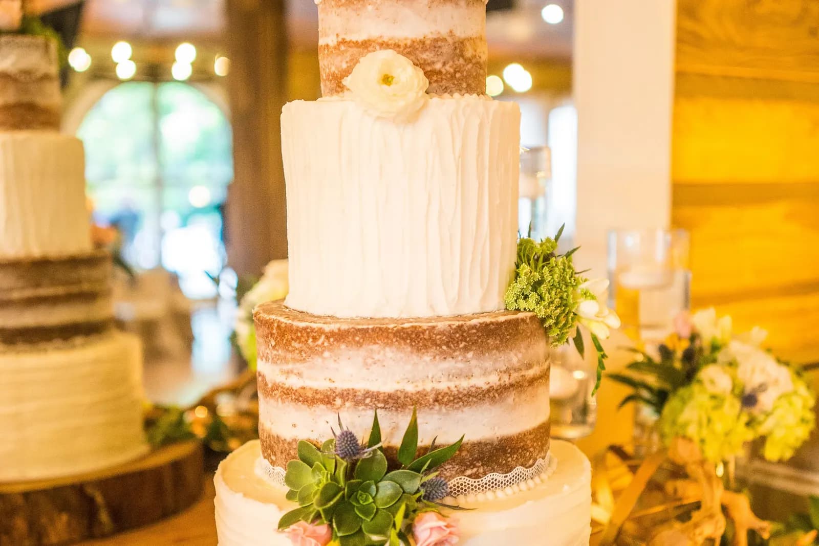 A rustic, lightly frosted cake decorated with fresh flowers and greenery