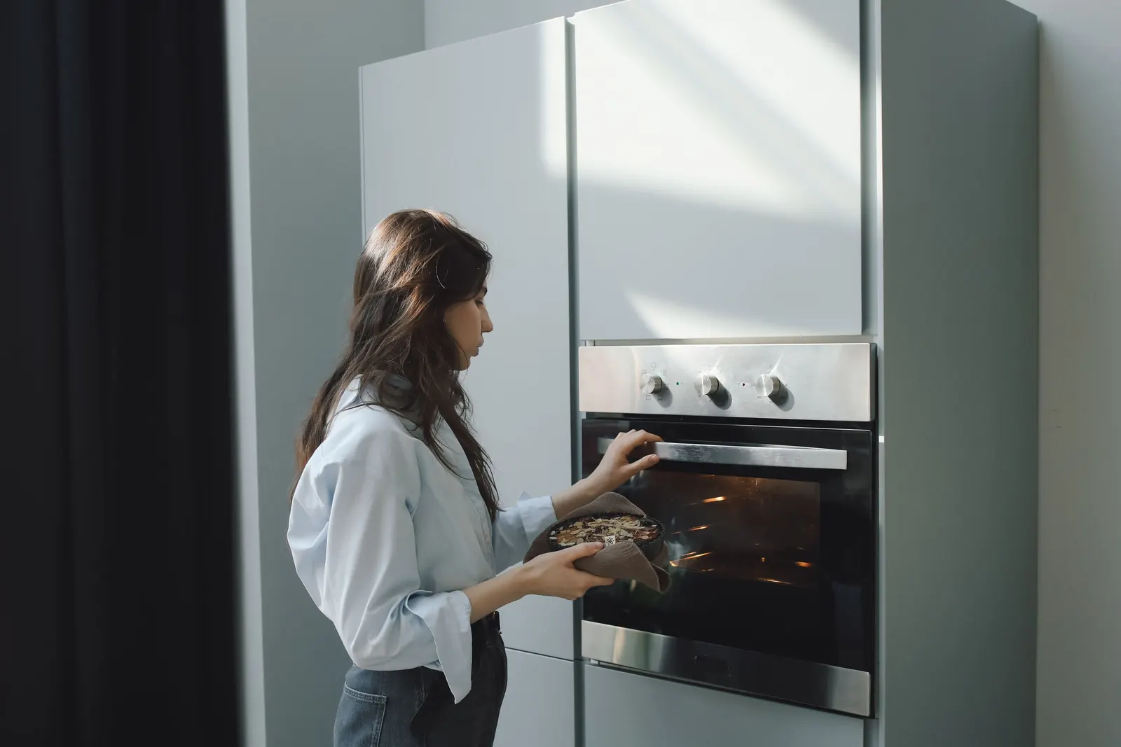 A woman placing a dish into the oven while baking at home