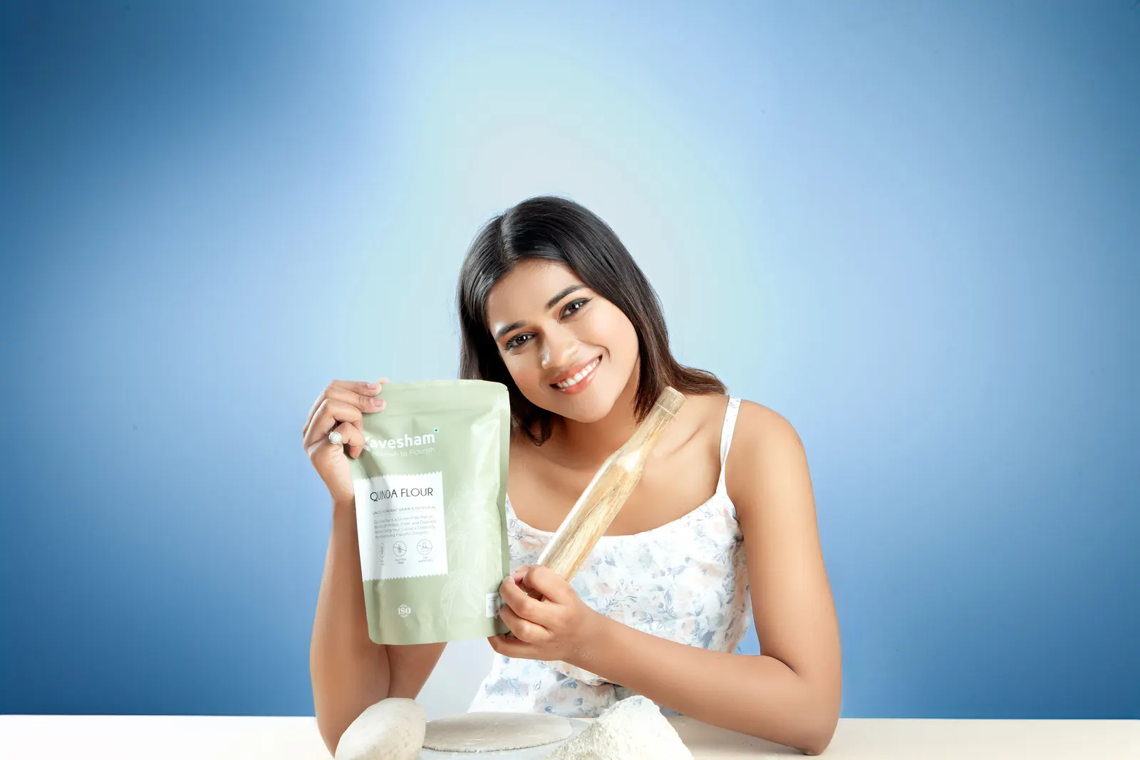 A smiling woman holding flour and a rolling pin, ready to bake
